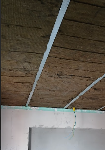 Forro acústico castanho no teto para isolamento térmico e acústico.
